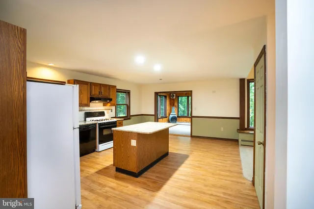 a kitchen with stainless steel appliances granite countertop a stove top oven a refrigerator a sink and dishwasher with wooden floor