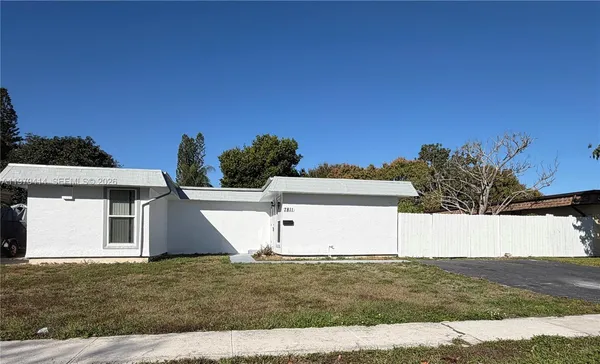 a view of a white house with a yard and a large tree