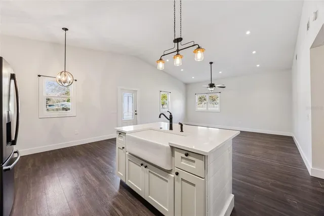 an empty room with wooden floor ceiling fan and windows