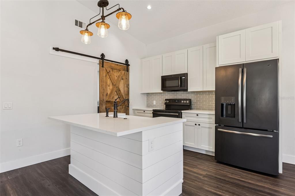 323 McLain Lane Geneva, FL 32732 - Photo 41 of 70 a kitchen with kitchen island white cabinets and stainless steel appliances