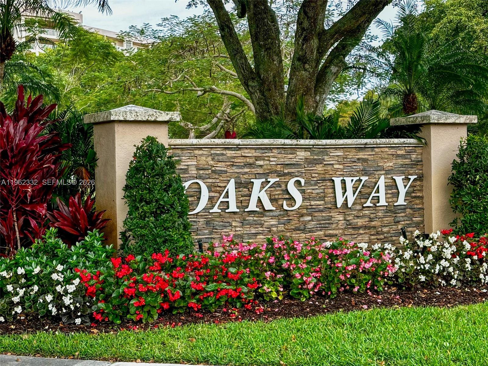 3510 Oaks Way, Unit 408 Pompano Beach, FL 33069 - Photo 2 of 27 a sign that is in front of flowers