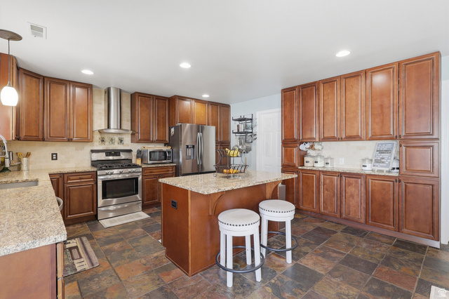 1652 West 800 South Lehi, UT 84043 - Photo 6 of 27 Kitchen featuring a kitchen breakfast bar, stainless steel appliances, a center island, light stone counters, and backsplash