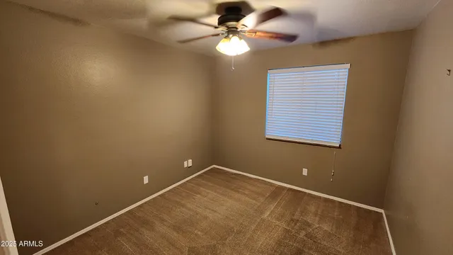 an empty room with a window and a fan