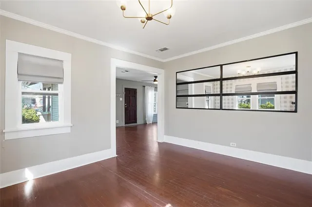 a view of an empty room with a window and wooden floor