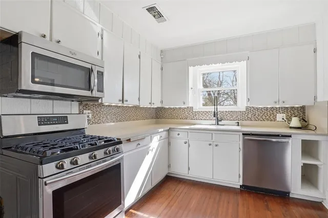 a kitchen with cabinets stainless steel appliances a sink and a wooden floor