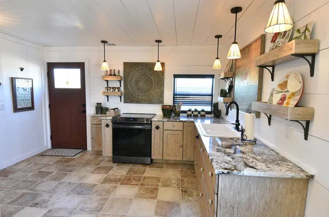 a kitchen with stainless steel appliances granite countertop a stove a sink and a refrigerator