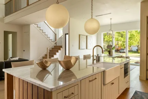 a kitchen with stainless steel appliances granite countertop a sink a counter top space and living room view