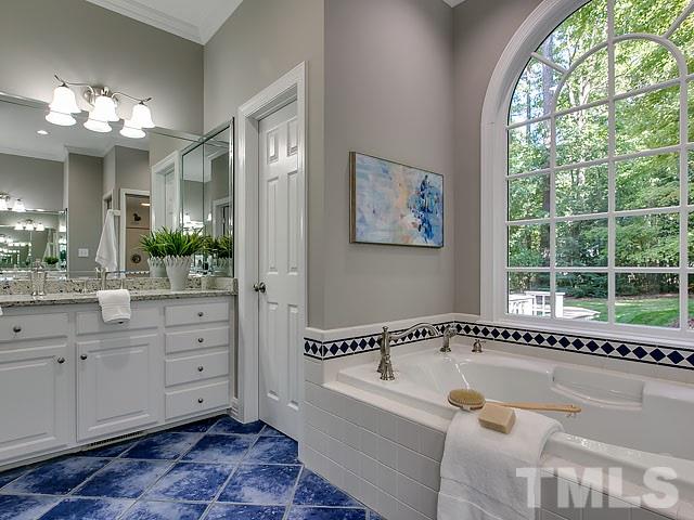 401 Mumm Lane Raleigh, NC 27615 - Photo 14 of 25 a spacious bathroom with a tub a double vanity sink a large mirror and a bathtub next to a window