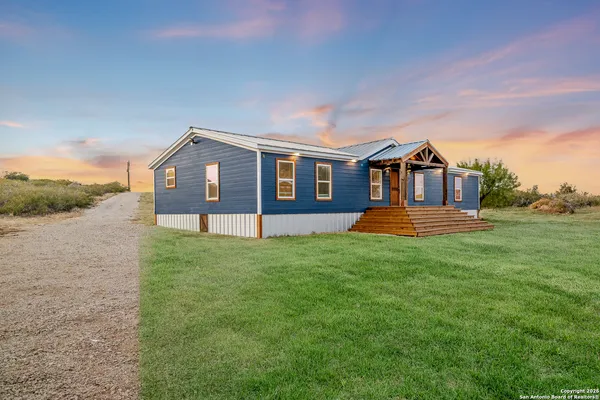 a front view of a house with a garden and trees