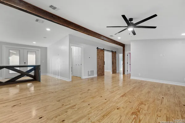 a view of empty room with wooden floor and fan