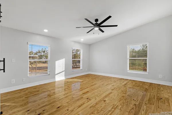 a view of an empty room with a window and wooden floor