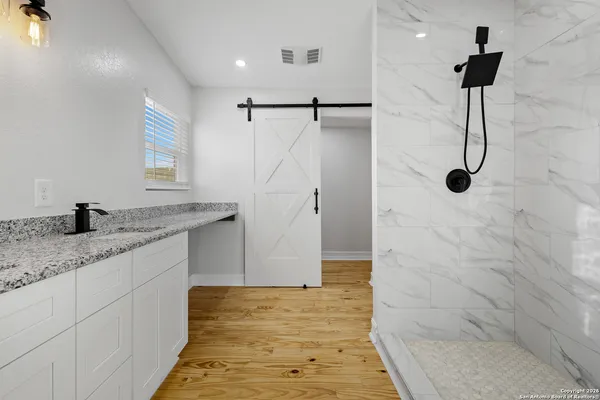 a bathroom with a granite countertop sink a shower and a mirror