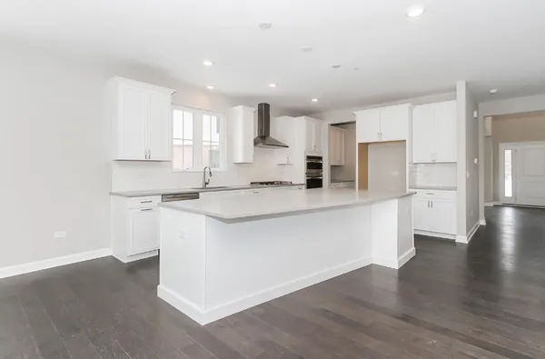 a kitchen with stainless steel appliances granite countertop a sink a stove a refrigerator and white cabinets