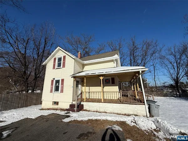 a view of a white house with a large tree