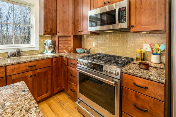a kitchen with stainless steel appliances granite countertop a sink stove microwave and refrigerator