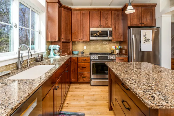 a kitchen with stainless steel appliances granite countertop a stove a sink and a microwave