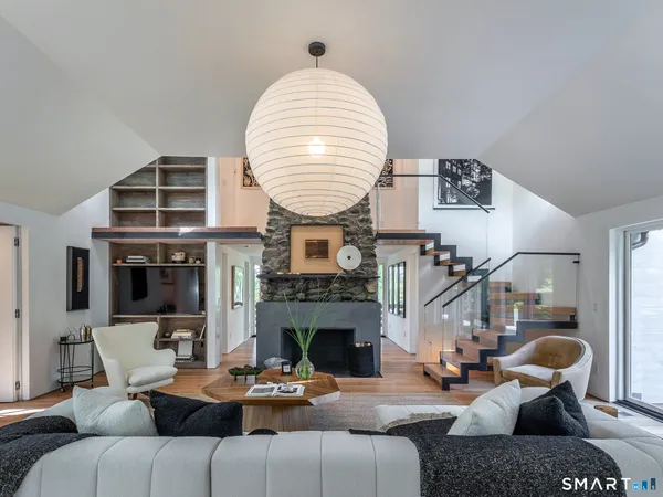 a living room with furniture a fireplace and a large mirror with wooden floor