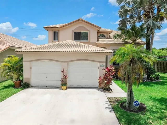 a view of a house with a yard and palm trees