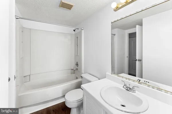 a bathroom with a bathtub shower sink vanity and toilet