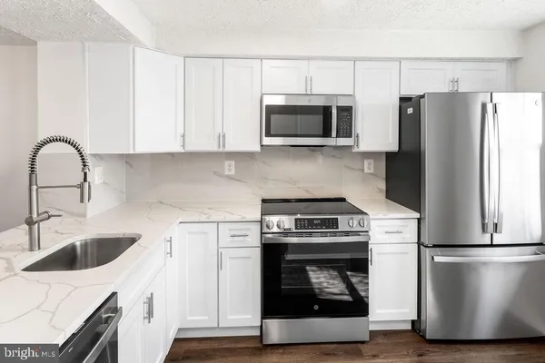 a kitchen with a sink stainless steel appliances and white cabinets