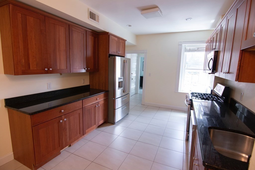 1897 Beacon Street, Unit 3 Brookline, MA 02445 - Photo 8 of 18 a kitchen with stainless steel appliances granite countertop a refrigerator and a sink