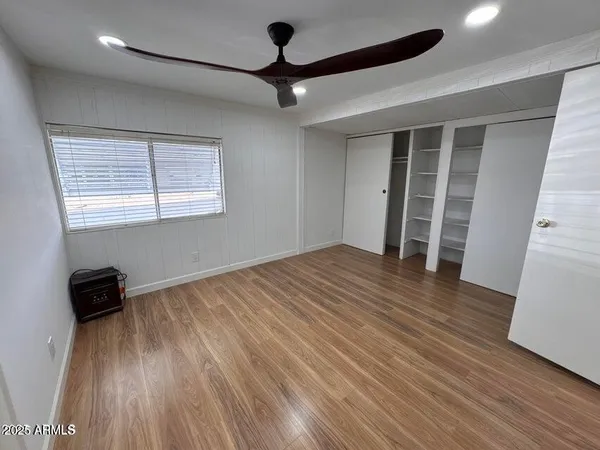 a view of empty room with wooden floor and fan