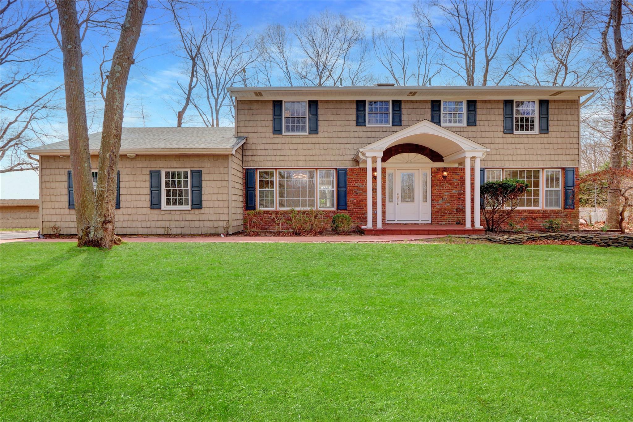 Colonial home with a front yard and brick siding