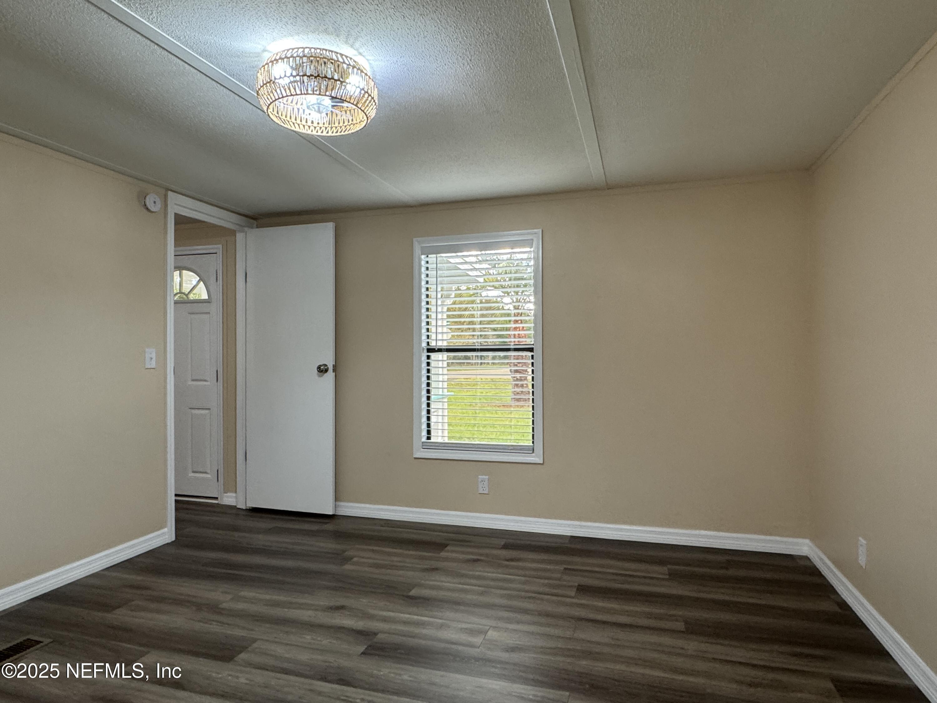 106 Ridgewood Avenue Interlachen, FL 32148 - Photo 9 of 23 an empty room with wooden floor and windows