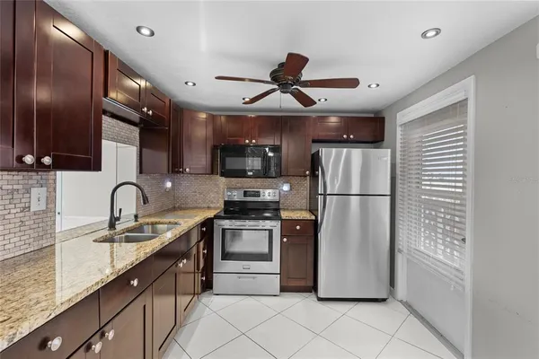 a kitchen with stainless steel appliances granite countertop a refrigerator a sink a stove a microwave and island