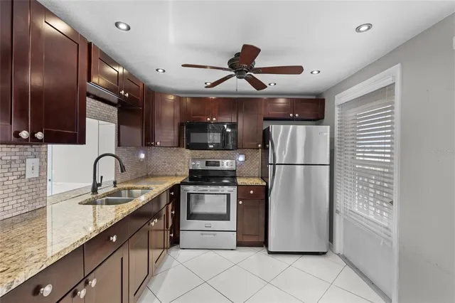 a kitchen with stainless steel appliances granite countertop a refrigerator a sink a stove a microwave and island