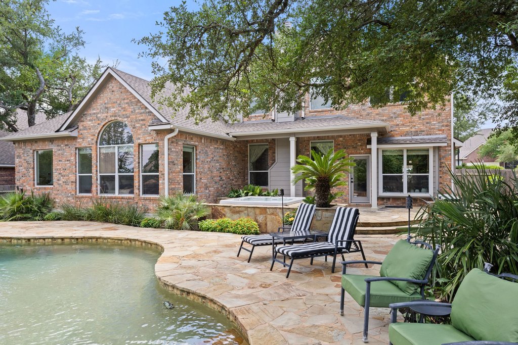 6704 Kiev Cove Austin, TX 78739 - Photo 4 of 37 A spacious backyard oasis features a freeform pool, a built-in spa, and a stone patio perfect for lounging.