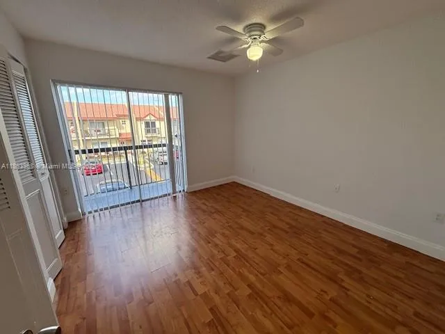 a view of a bedroom with wooden floor and a ceiling fan