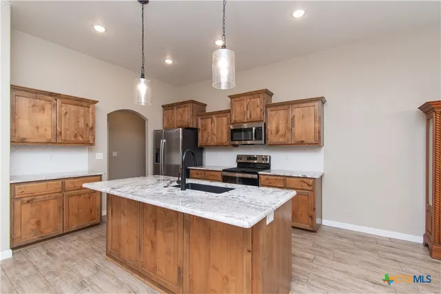 a kitchen with stainless steel appliances granite countertop a sink a stove and a wooden floors