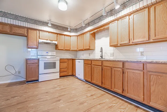 a kitchen with stainless steel appliances granite countertop a stove a sink dishwasher and a refrigerator