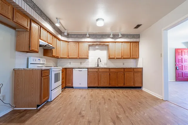a kitchen with stainless steel appliances kitchen island granite countertop a sink cabinets and wooden floor