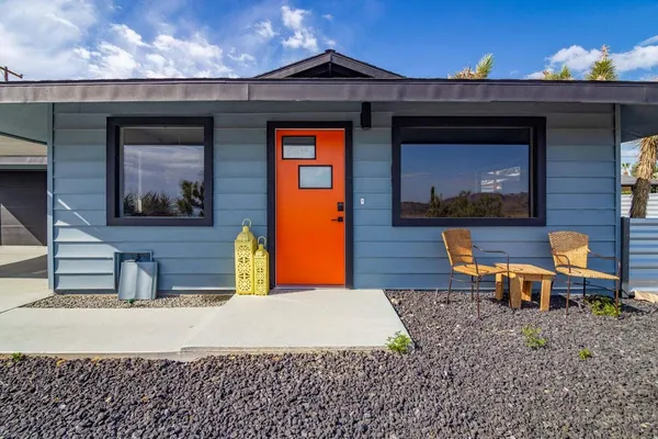 a backyard of a house with wooden table and chairs