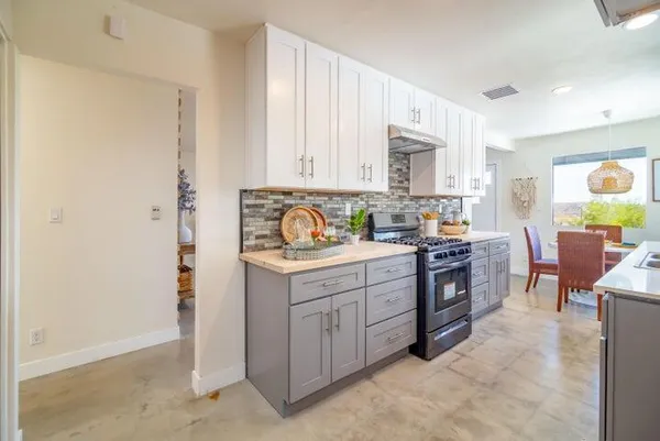 a kitchen with stainless steel appliances granite countertop a stove top oven a sink dishwasher and a refrigerator with wooden floor