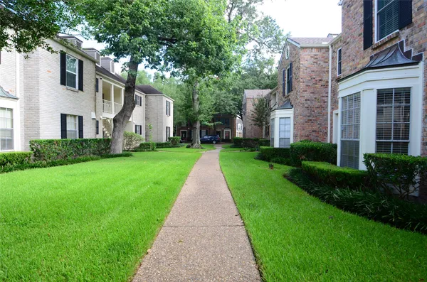 a view of a big yard in front of a brick house with plants