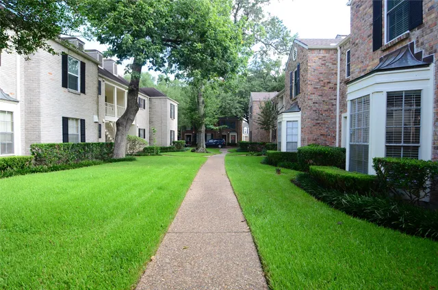 a view of a big yard in front of a brick house with plants