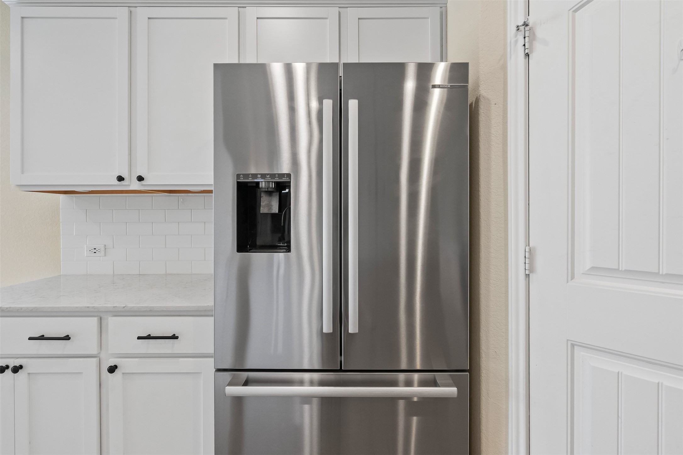 4125 Buffalo Ford Road Georgetown, TX 78628 - Photo 7 of 28 Kitchen featuring stainless steel refrigerator with ice dispenser, tasteful backsplash, white cabinetry, and light stone countertops