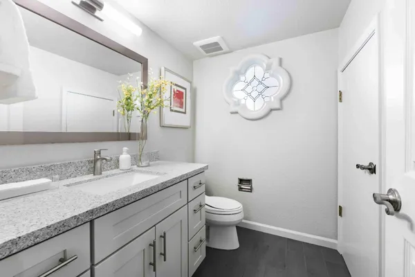 a bathroom with a granite countertop toilet sink and mirror