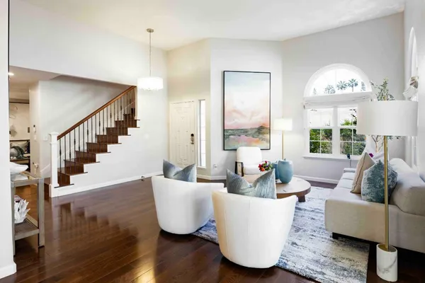 a living room with couches and a potted plant on table with wooden floor