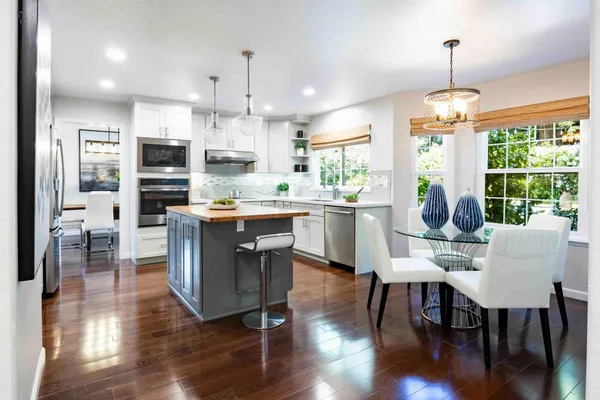 a dining room with stainless steel appliances granite countertop furniture wooden floor and a kitchen view
