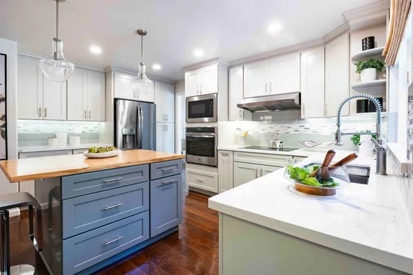 a kitchen with kitchen island granite countertop stainless steel appliances a sink cabinets and refrigerator