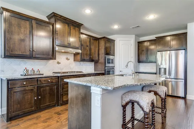 a kitchen with stainless steel appliances granite countertop a sink stove and refrigerator