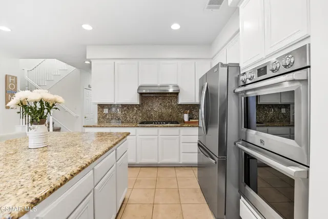 a kitchen with stainless steel appliances granite countertop a refrigerator sink and stove