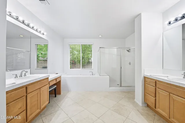 a spacious bathroom with a double vanity sink a mirror and a bathtub