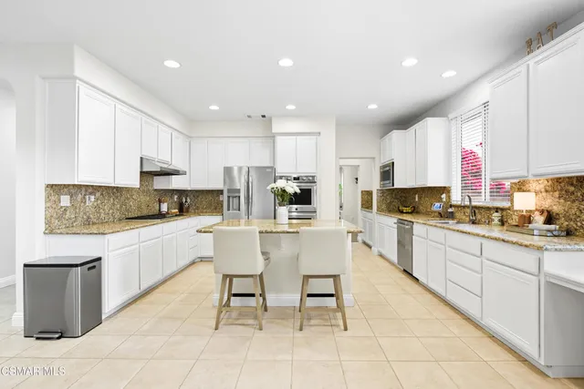 a kitchen with stainless steel appliances granite countertop a sink and a refrigerator