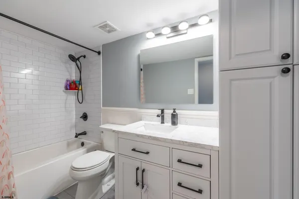 a bathroom with a granite countertop sink a toilet a window and a mirror