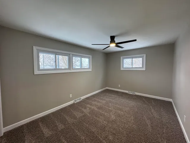 a view of a livingroom with a ceiling fan & windows